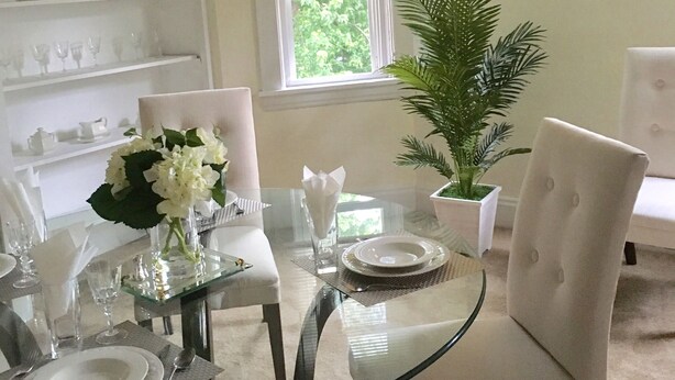 A dining area with a glass table, white chairs, and a potted plant. -  Minutes from Downtown, Pittsburgh’s international airport,  & Sports’ arenas! (Pittsburgh)