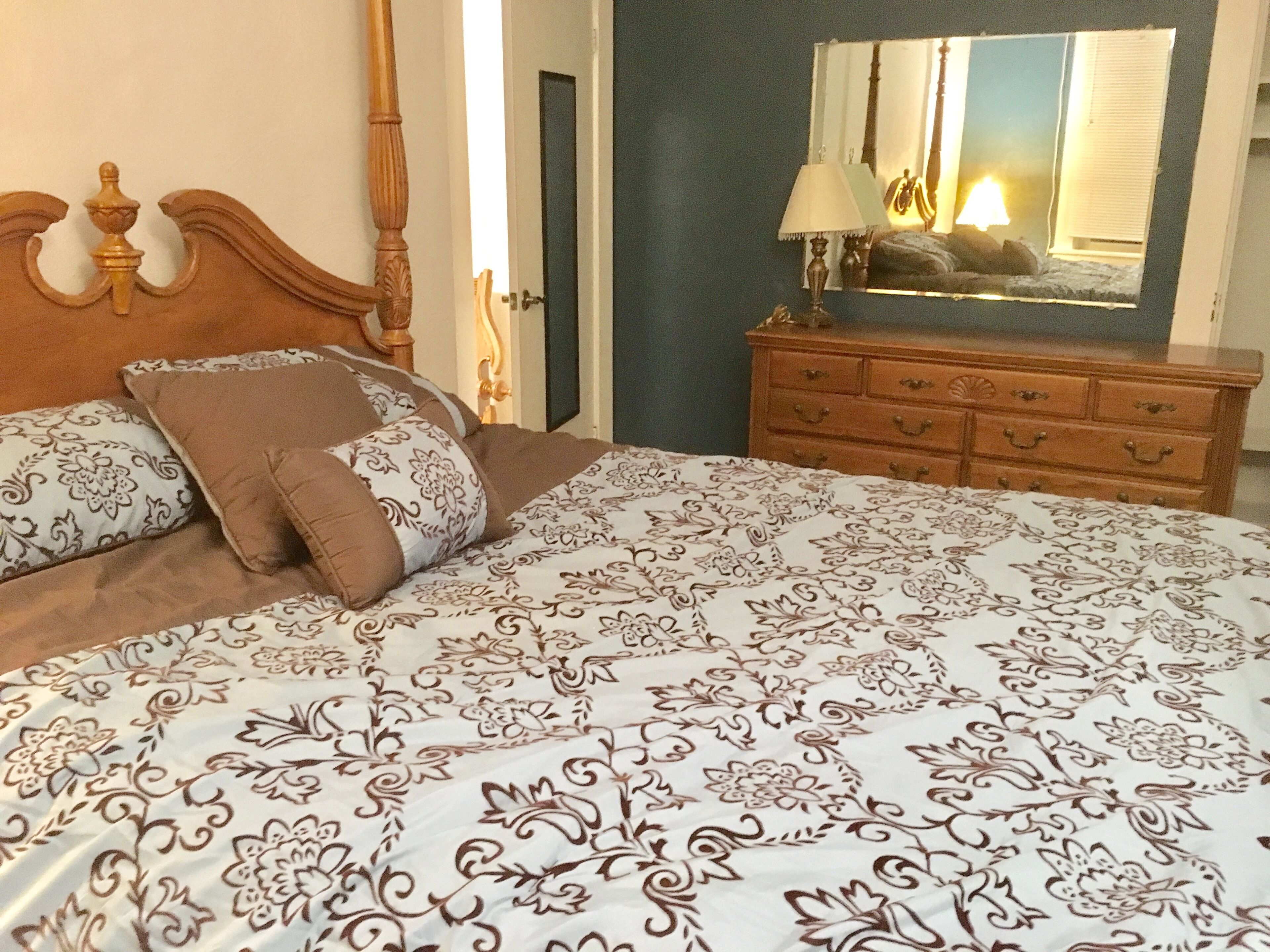 A bedroom with a bed, a dresser, and a mirror.