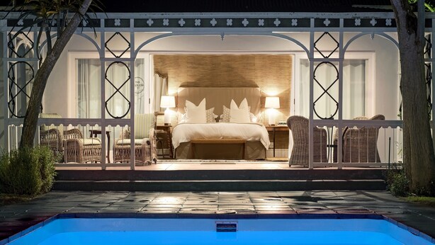 Un dormitorio con una cama grande, dos lámparas de noche y muebles de mimbre.