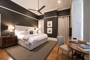 A bedroom with a bed, bedside tables, a chair, and a desk with books and a lamp.
