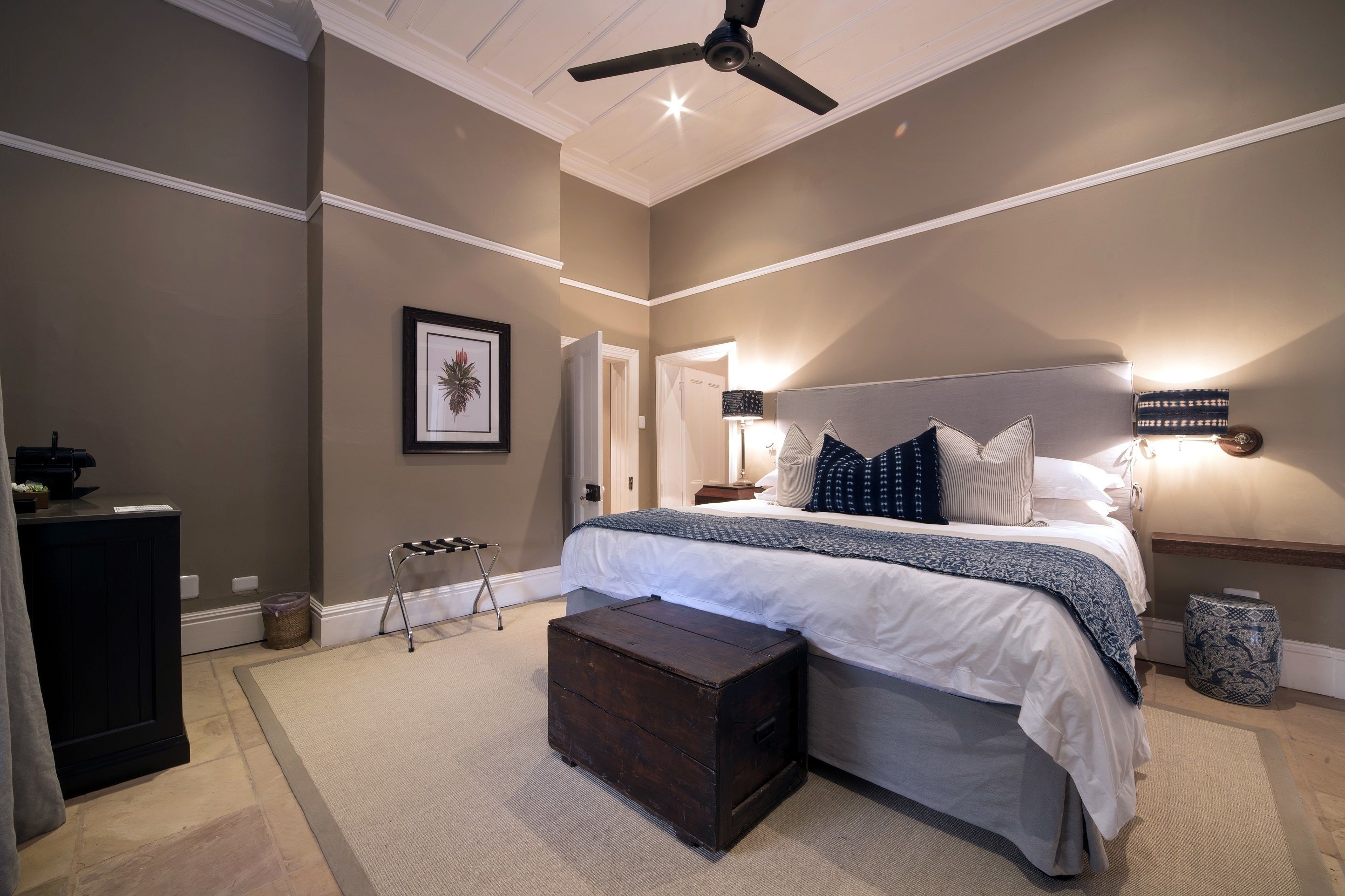 A bedroom with a bed, bedside tables, a ceiling fan, and a nightstand.