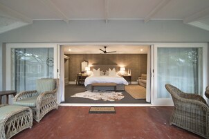 Un dormitorio amplio con una cama grande, un ventilador de techo y vistas a través de una puerta abierta.