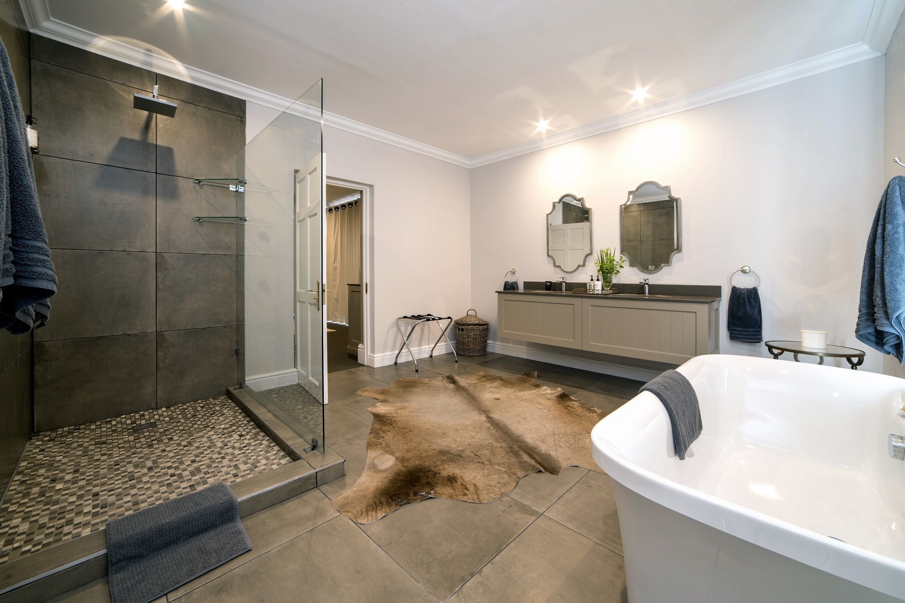 A modern bathroom with a walk-in shower, a large bathtub, and a vanity with a mirror.