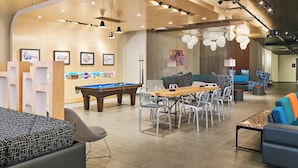 Un espace de détente moderne comprenant une table de billard, des sièges confortables et un coin repas informel.