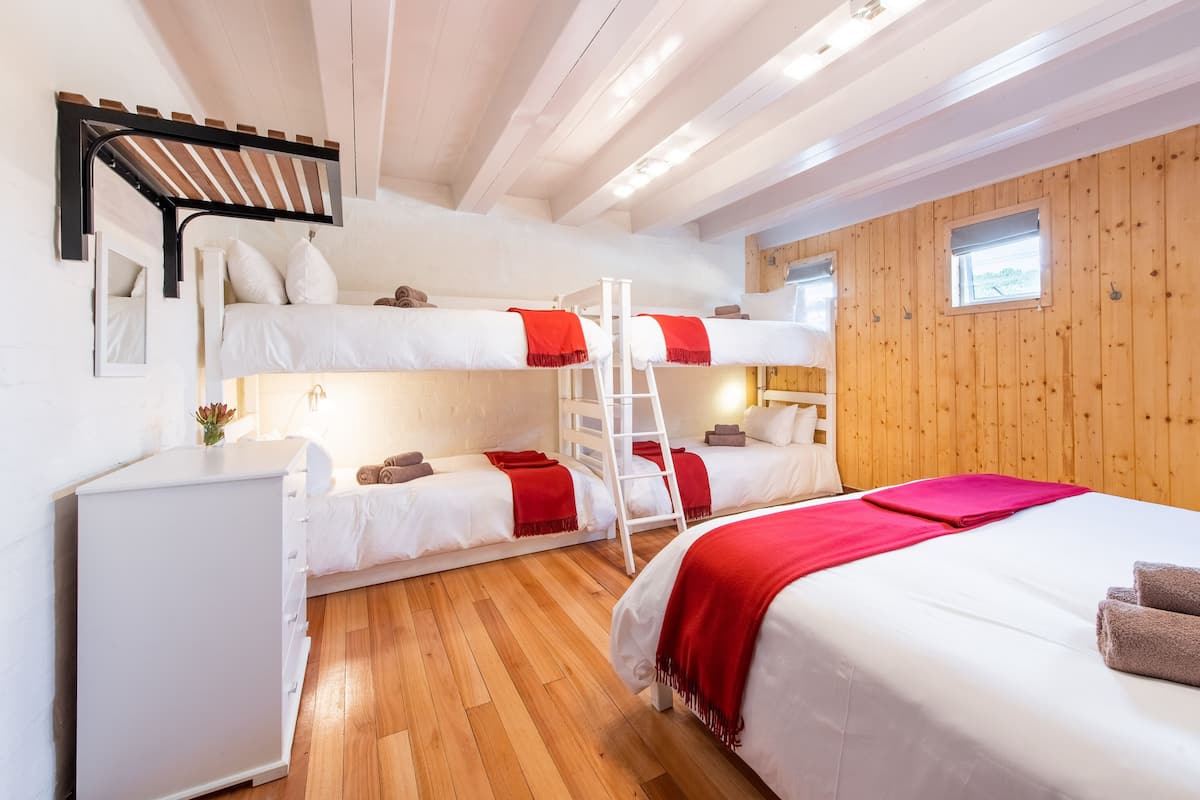 A bunk bed room with a ladder, a desk, and a window.
