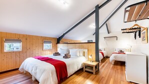 A bedroom with a large bed, two bedside tables, a wardrobe, and a hanging rack. - Trails End Bike Hotel (Grabouw)