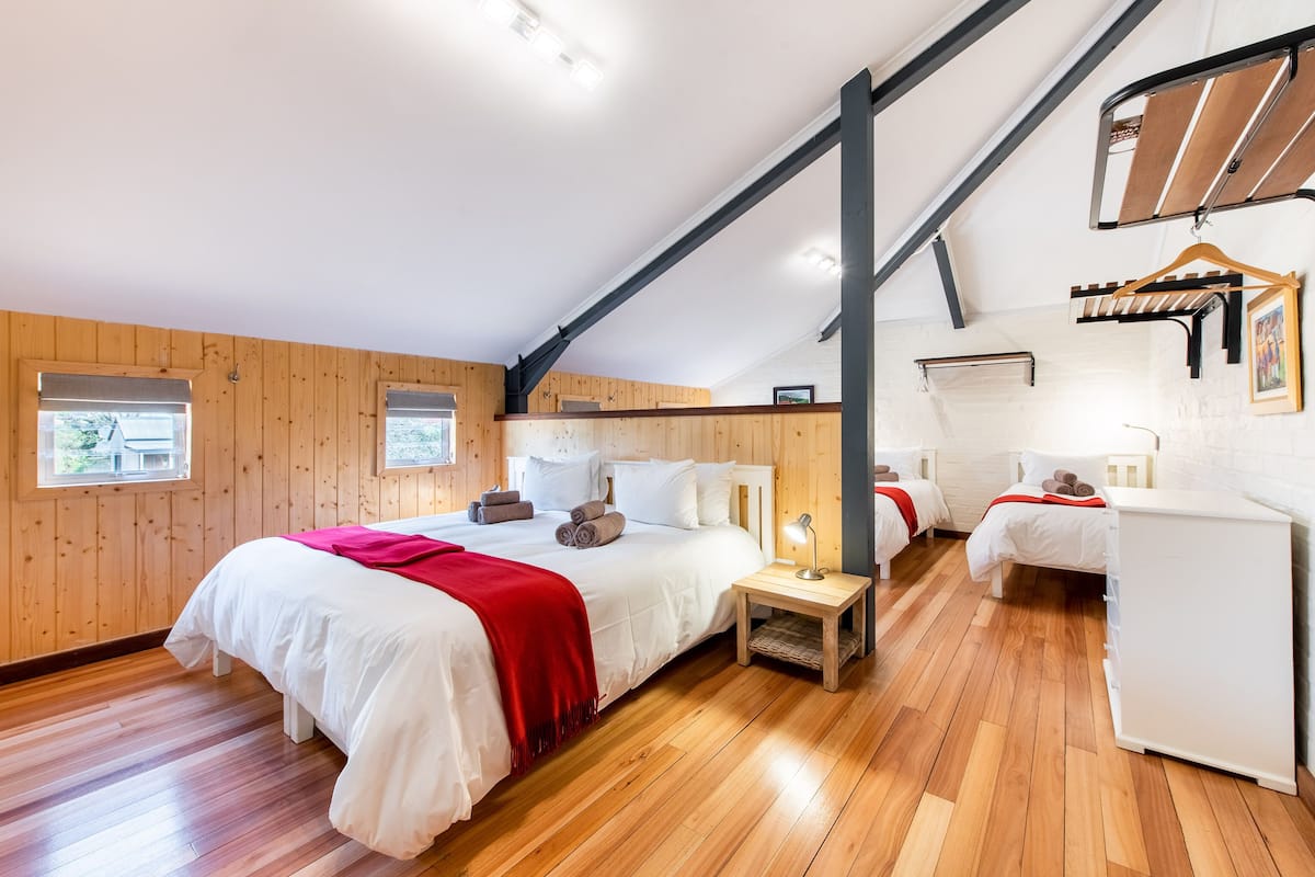 A bedroom with a large bed, two bedside tables, a wardrobe, and a hanging rack.