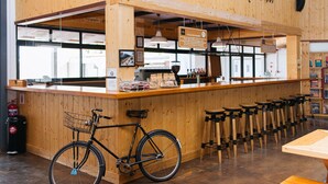 A wooden bar area with a bicycle, stools, and a sign indicating a 'Cycle for Change' initiative. - Trails End Bike Hotel (Grabouw)