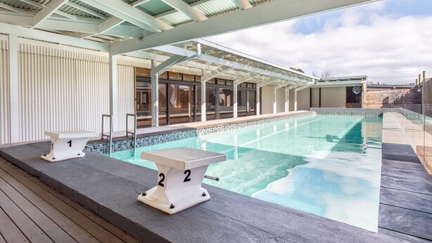 A swimming pool with numbered diving boards, a covered seating area, and a view of the sky. - Trails End Bike Hotel (Grabouw)