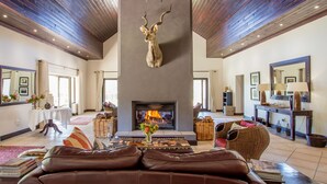 A spacious living room with a fireplace, leather sofas, and a large mirror. - Wildehondekloof (Oudtshoorn)