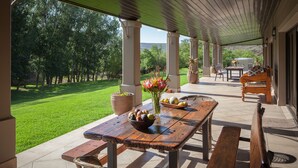 An outdoor patio with a wooden table, benches, and potted plants. - Wildehondekloof (Oudtshoorn)