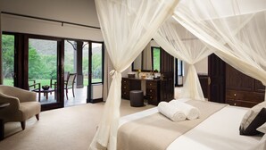 A bedroom with a large bed, a chair, a desk, and a view of the outdoors. - Wildehondekloof (Oudtshoorn)