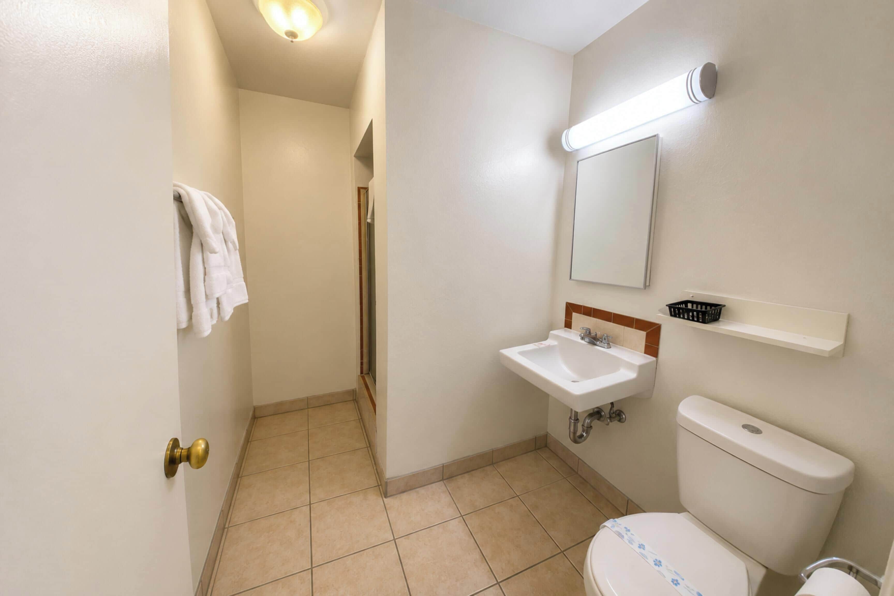 Ein Badezimmer mit Toilette, Waschbecken, Spiegel und Handtuchhalter.