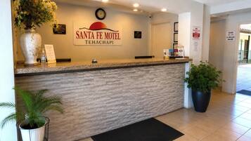 Una mesa de recepción en Santa Fe Motel, con un reloj, un cartel y una planta en maceta.