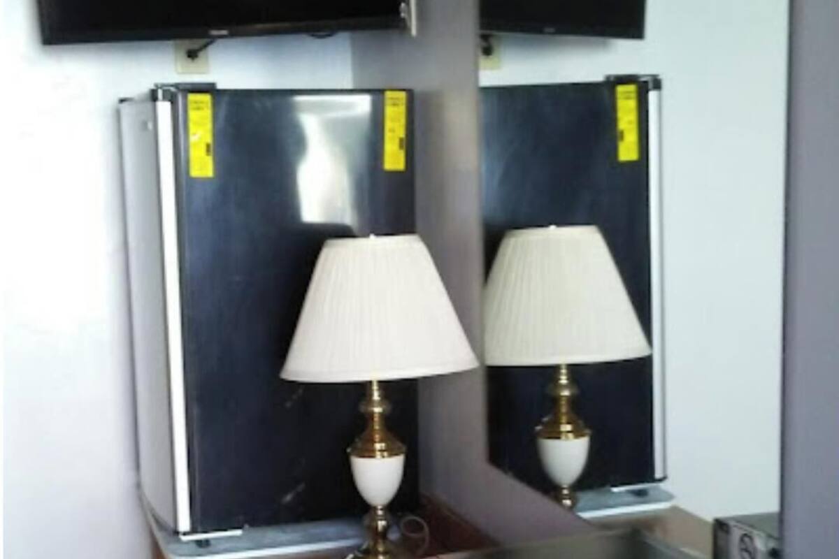 Een kleine kamer met een houten dressoir, een rode magnetron en twee wandkoelkasten.