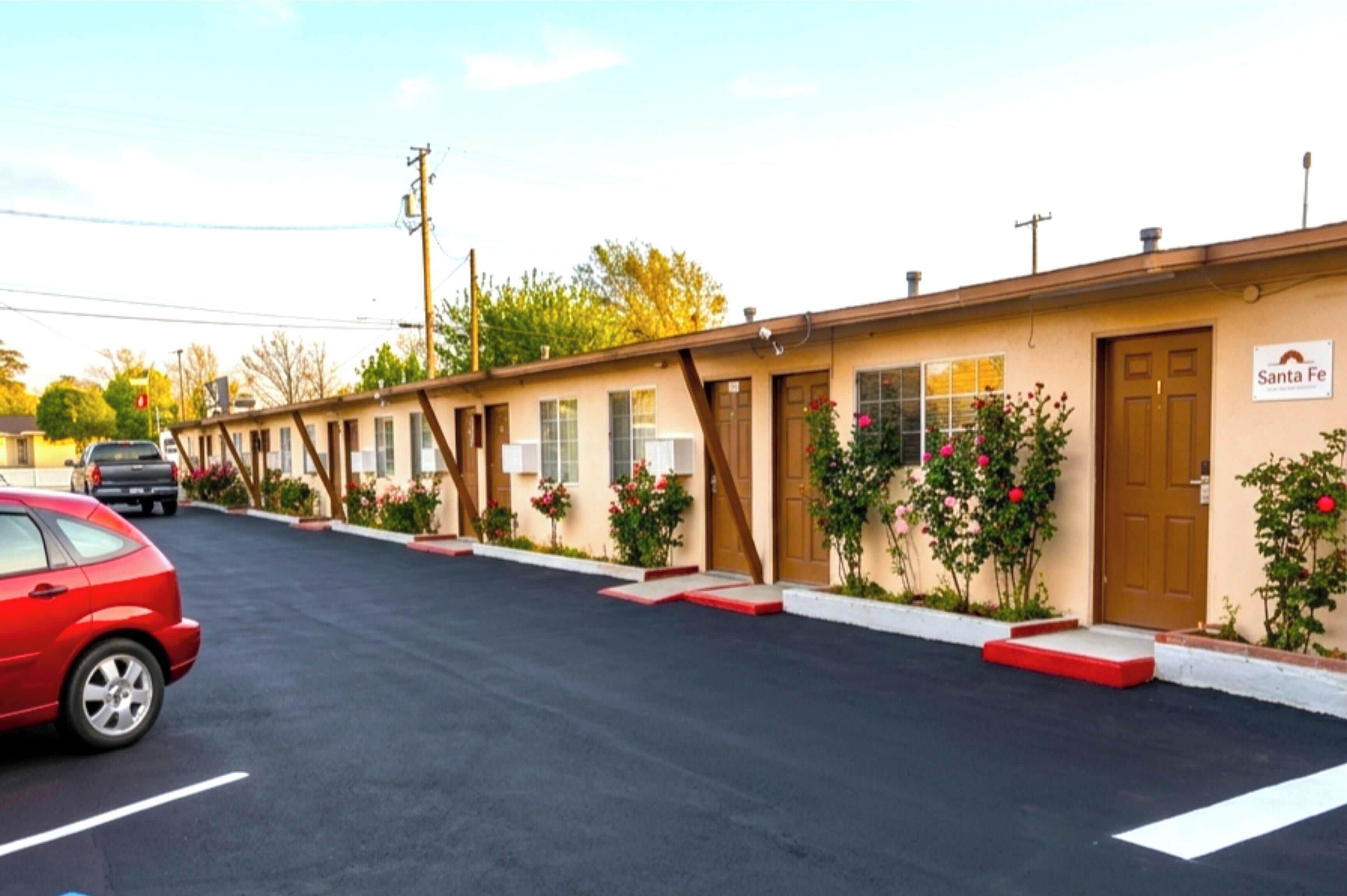 Un motel con una fila de habitaciones, un estacionamiento y un cartel que dice 'Santa Fe'.
