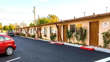 Un motel con una fila de habitaciones, un estacionamiento y un cartel que dice 'Santa Fe'.