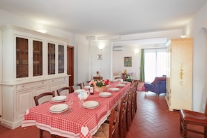 A dining room with a long table set for four, flanked by wooden cabinets and chairs.