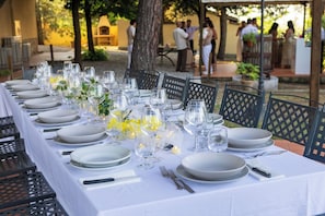A table set for a meal with chairs, a white tablecloth, and a small decorative plant.