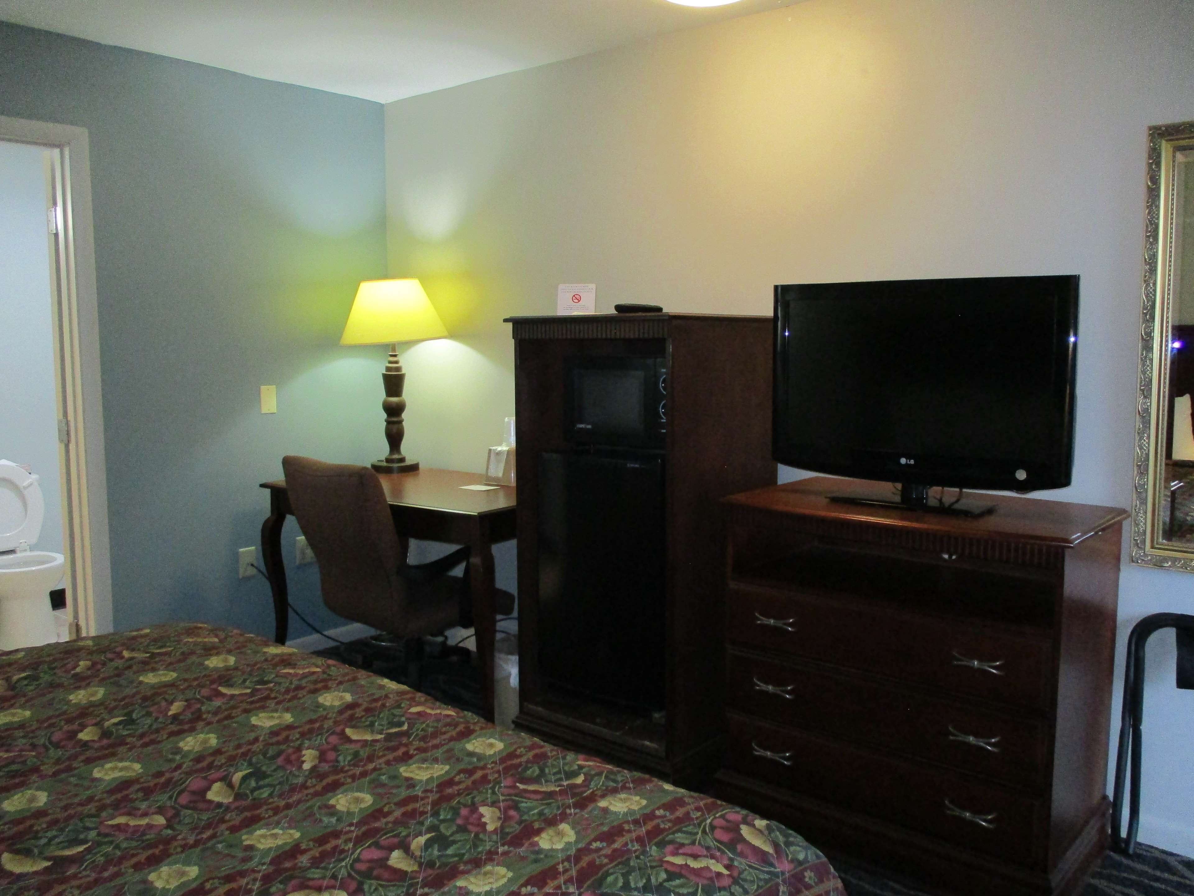 Une chambre d’hôtel équipée d’un lit, d’un bureau, d’une télévision et d’une commode.