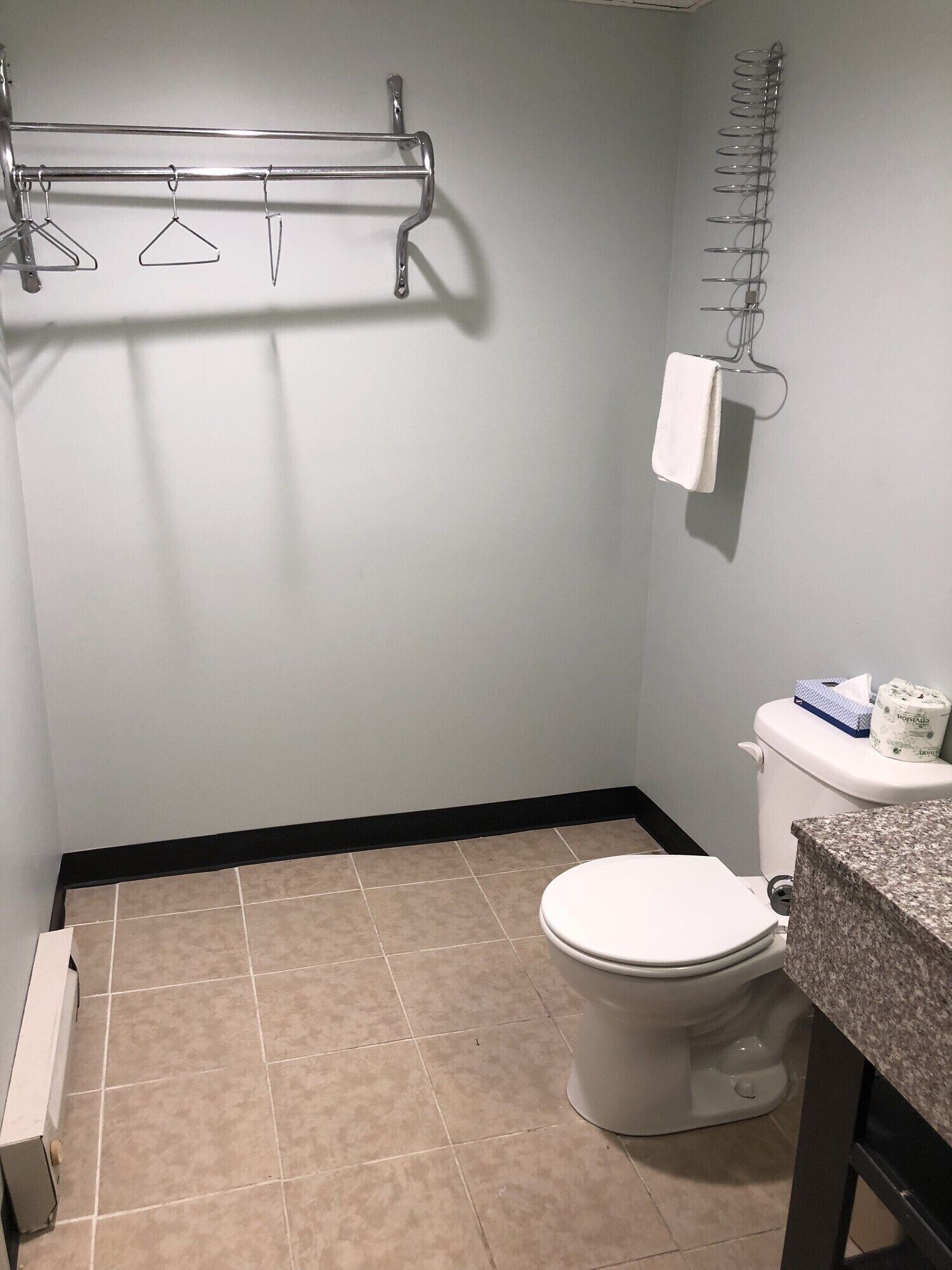 A bathroom with a toilet, a towel rack, and a toilet paper holder.