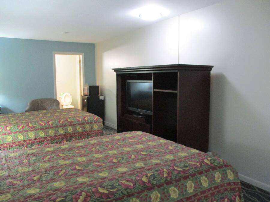 A hotel room with two beds, a television, a desk, and a chair.
