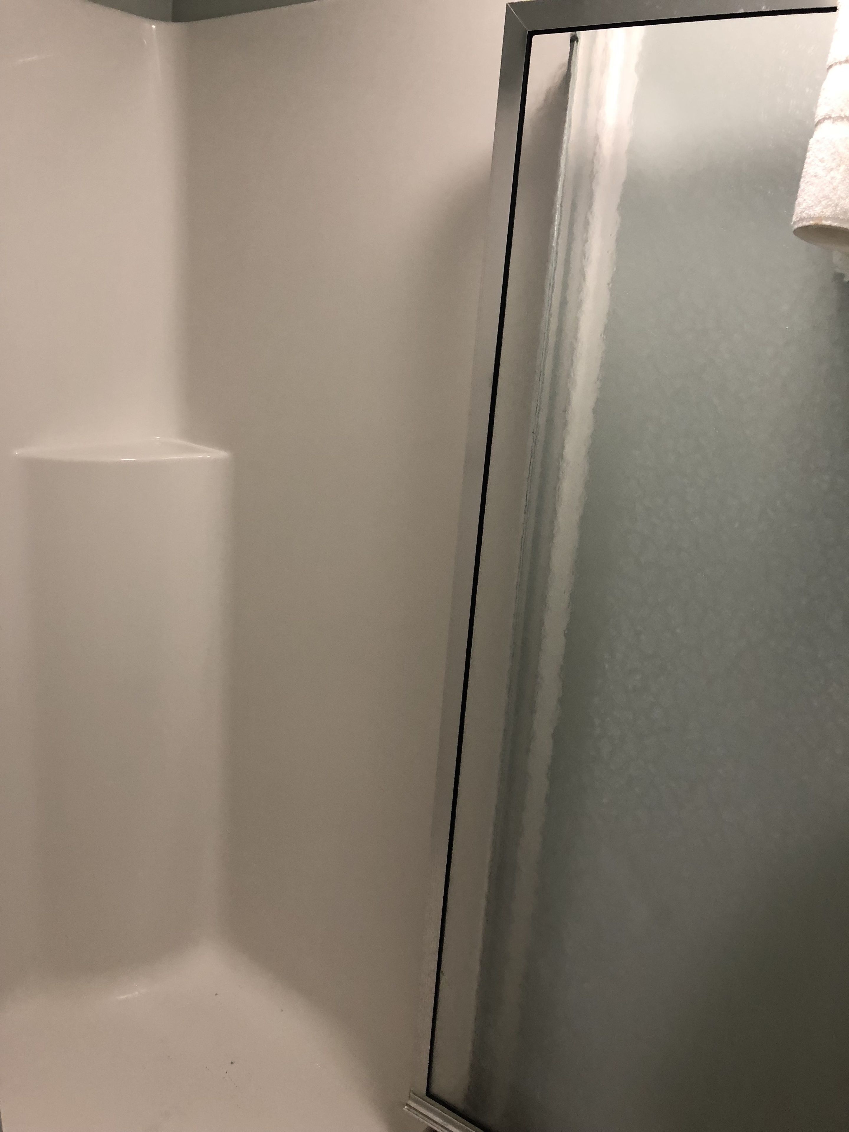 A bathroom with a white bathtub, a shower area, and a metallic door.