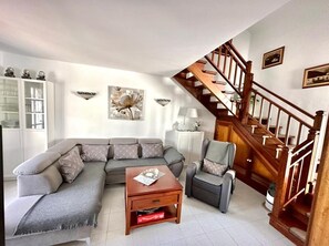 A living room with a sofa, armchair, coffee table, and a staircase.