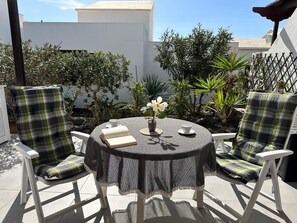A round table with a lace tablecloth, two plaid chairs, a potted plant, and a book. - Dlx - Bungalow. Fantastic private complex directly by the sea pool, fiber optic internet (Playa Honda)