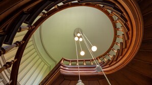 Una imponente escalera de caracol con detalles de madera y una puerta blanca al final.