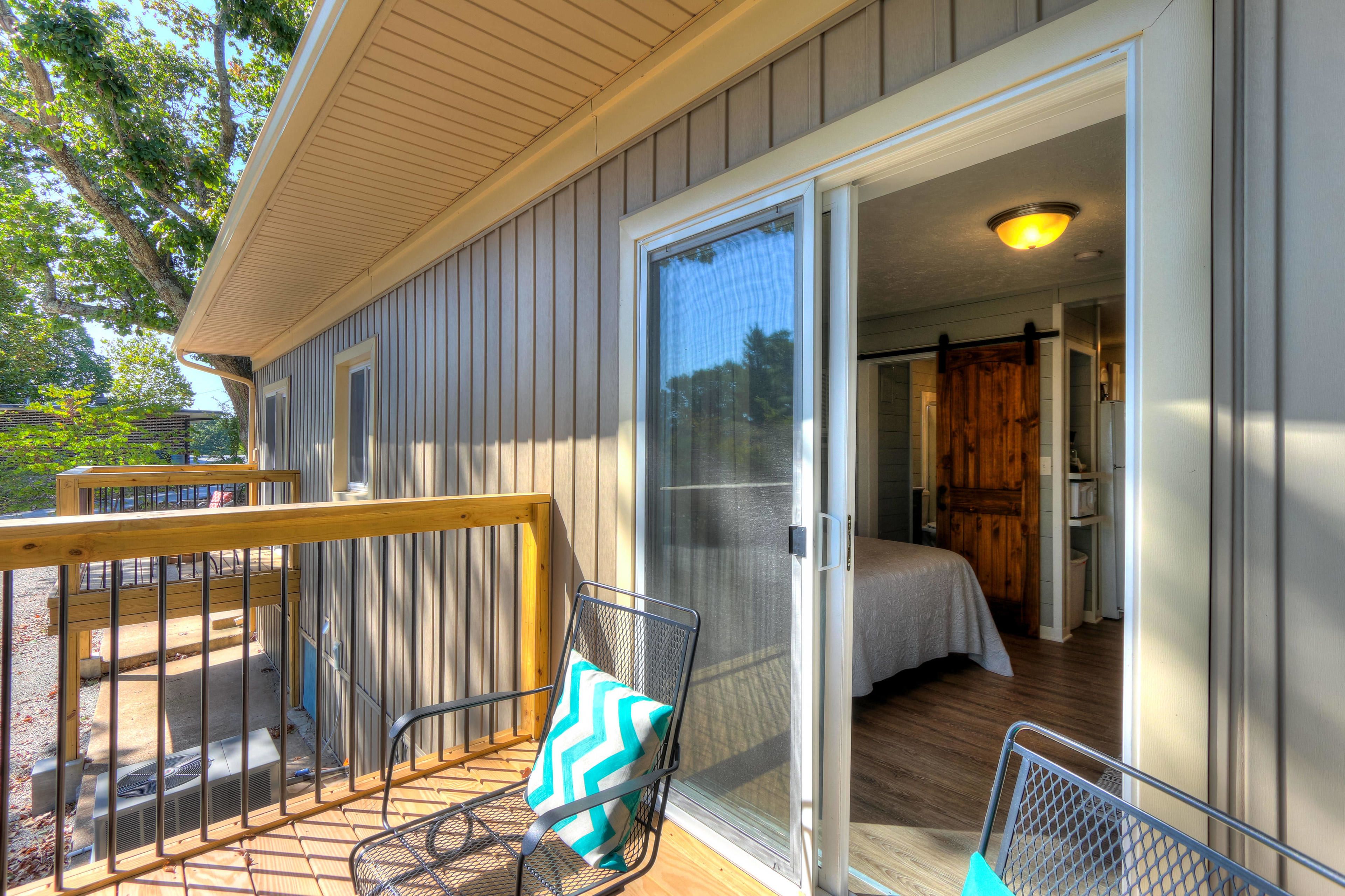 A room with a bed, a wooden door, and a sliding glass door leading to a balcony.
