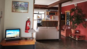 Un hall d’entrée avec un comptoir de réception, un canapé, un extincteur, un ordinateur portable et un tableau accroché au mur.