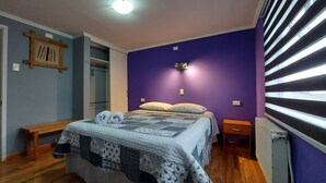 Une chambre à coucher comprenant un lit, deux tables de chevet, une commode, une armoire et un radiateur.