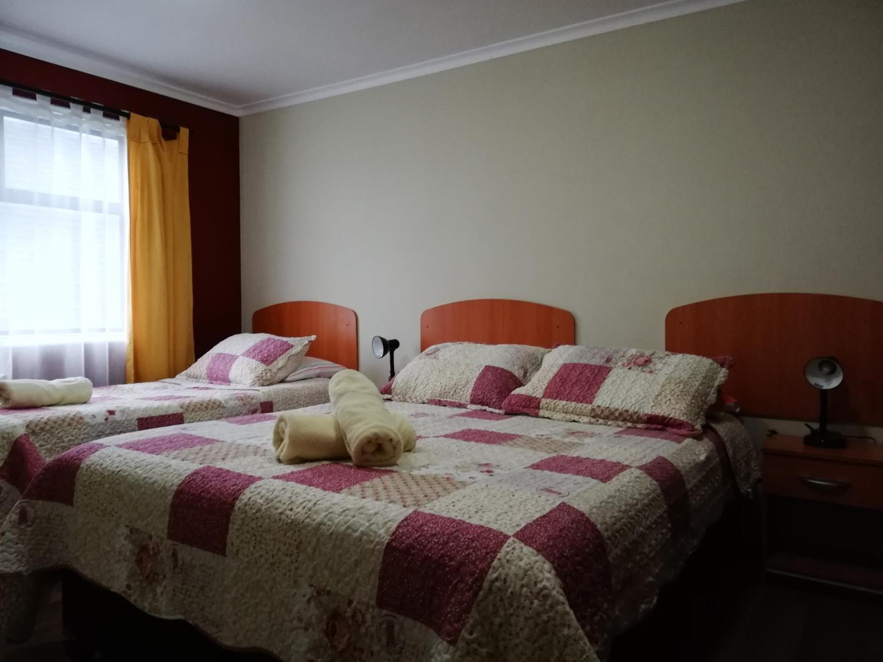 Une chambre d’hôtel avec deux lits, chacun étant agrémenté d’une couvre-lit matelassé et de coussins. Il y a deux tables de chevet avec des lampes.