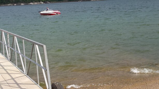 Un muelle de concreto con un letrero que dice 'NO FISHING', un neumático y un bote en el agua.