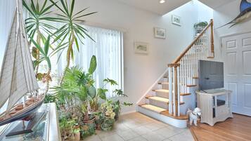 Relax in this spacious living area with a high ceiling, skylight, and lush greenery.