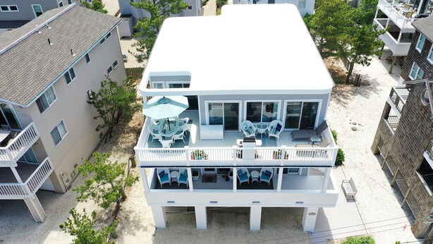 A two-story beachfront property with a balcony and outdoor seating area. - 2027_Ocean View Completely upgraded-New everything_ 2027 Rates (Harvey Cedars)