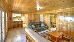 A wooden interior with a sofa, chairs, a table, and a kitchen area. - Lake-front Cabin Located In The Heart Of Bear Lake! (Garden City)
