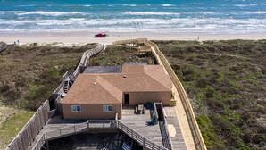 A beach house with a wooden deck and a view of the ocean.