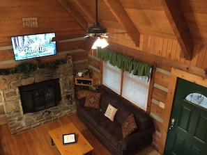 Cozy cabin-style room with a fireplace, sofa, and television.