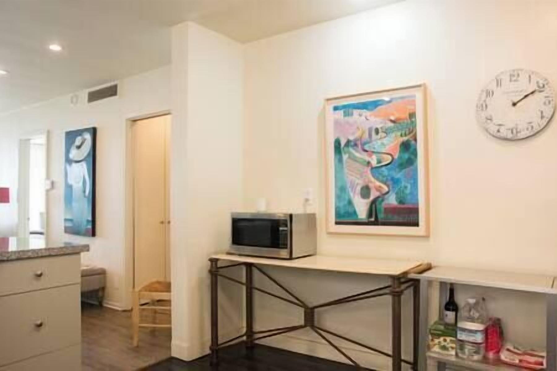 Una cocina moderna con un microondas sobre un mueble, un cuadro en la pared y un reloj.