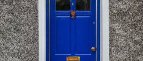 A blue door with a white arch above it, flanked by two potted plants.