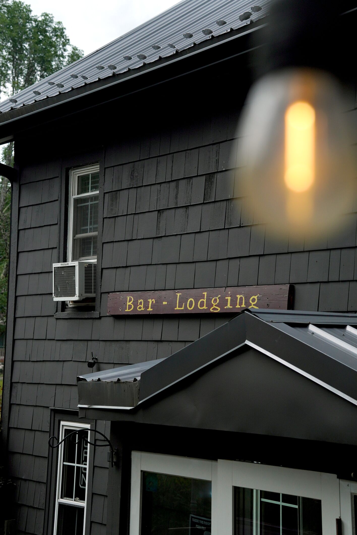A building with a sign reading 'Bar-Lodging' and an air conditioning unit mounted on the exterior wall.