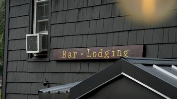 A building with a sign reading 'Bar-Lodging' and an air conditioning unit mounted on the exterior wall.