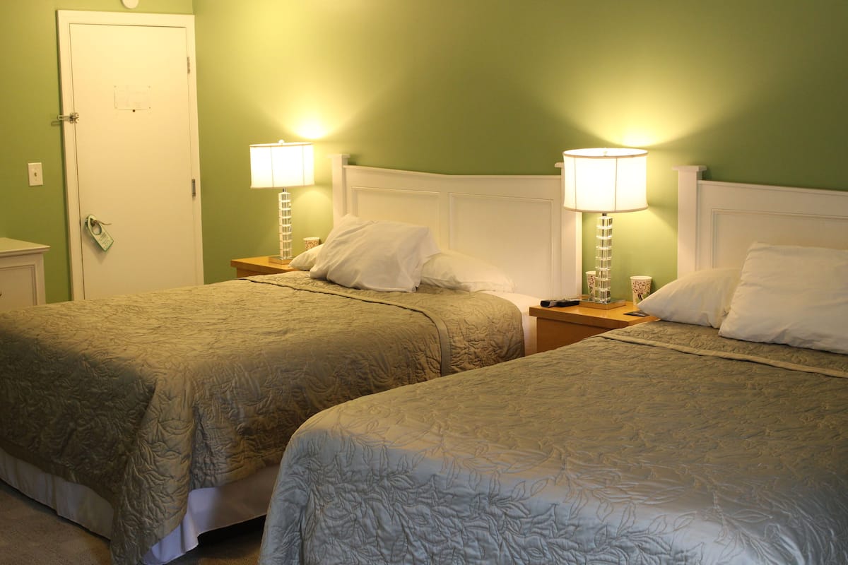 Two single beds with headboards, bedside tables with lamps, and a door with a lock.