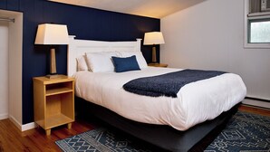 A neatly made bed with a white headboard, two bedside lamps, and a dark blue throw blanket.