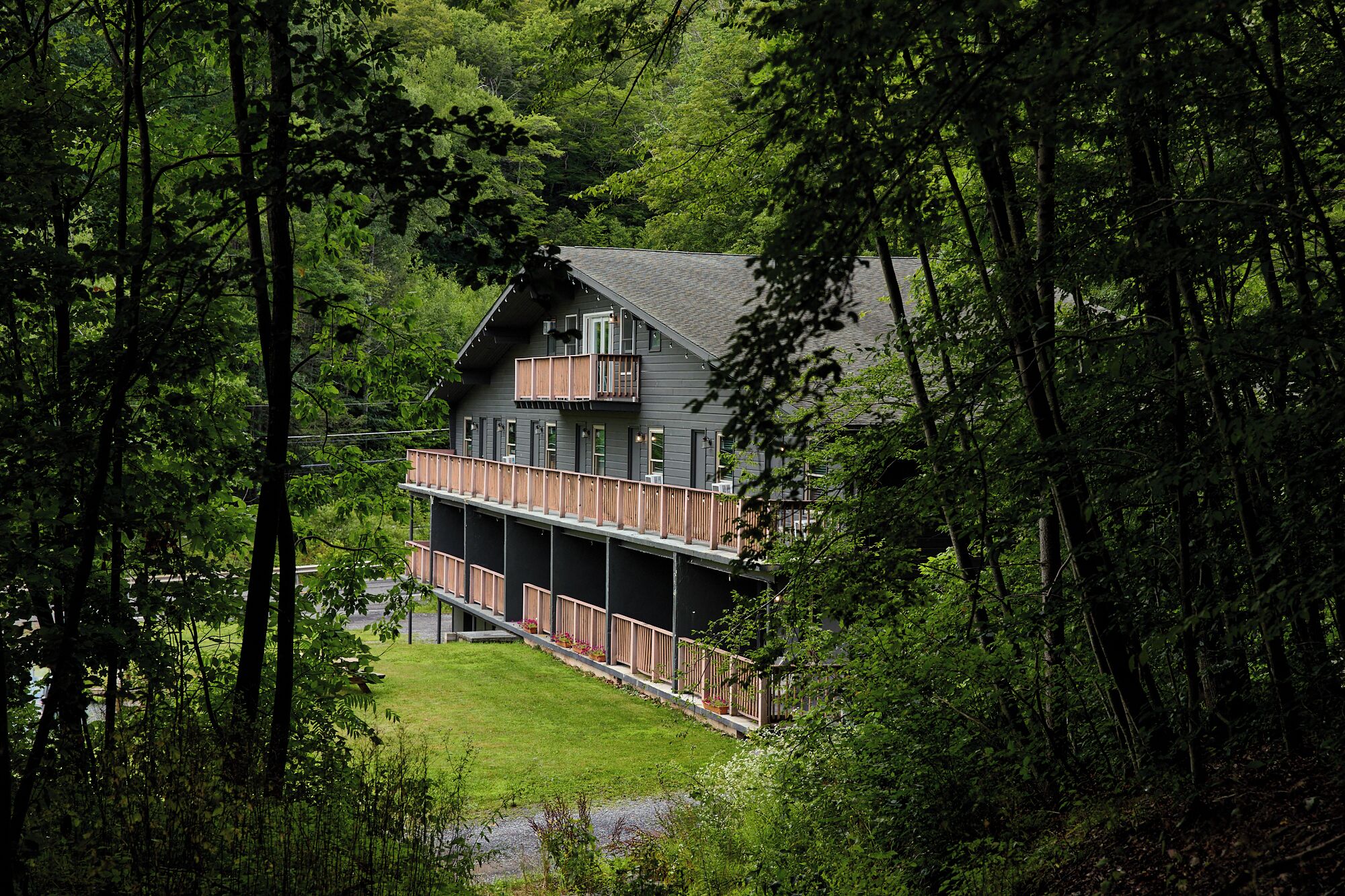 A two-story building with a balcony, surrounded by dense forest.