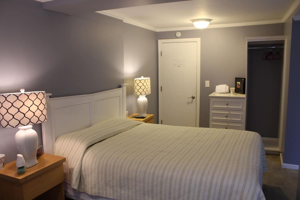 A bedroom with a bed, nightstands, a dresser, and a door.
