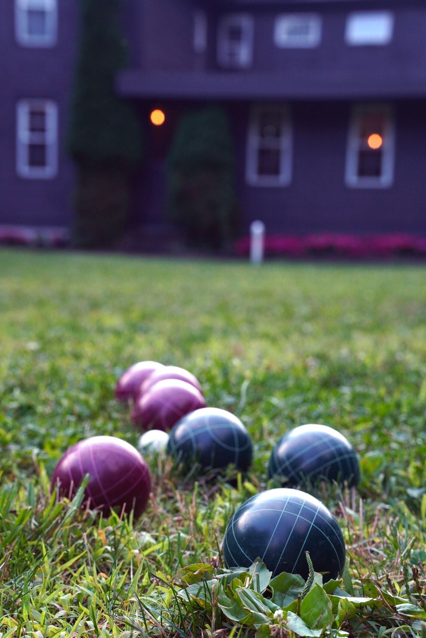 A grassy area with several spherical objects, a building in the background, and a clear sky.