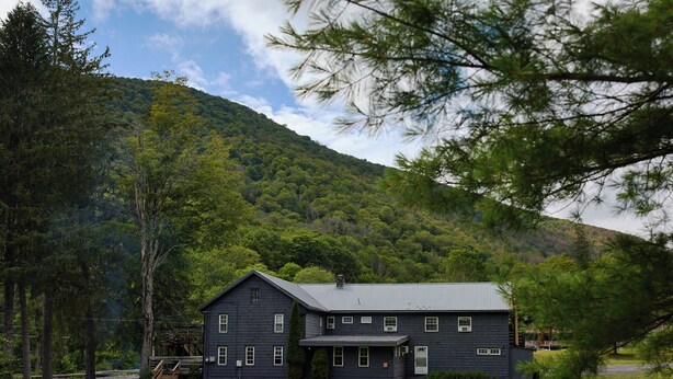 A two-story building with a dark exterior, surrounded by a grassy area with picnic tables.